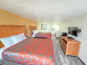 a hotel room with a bed and a flat screen tv at Peach City Inn - Marysville/Yuba City in Marysville