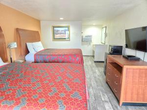 Peach City Inn - Marysville/Yuba City في ماريسفيل: غرفة فندقية بسرير وتلفزيون بشاشة مسطحة