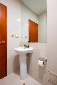 een witte badkamer met een wastafel en een spiegel bij Rits Apart Hotel in Lima