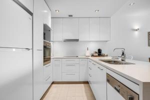 a white kitchen with white cabinets and a sink at Luxury Breeze Beachfront Apartment in Victor Harbor