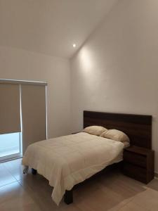 a bedroom with a bed and a white wall at Alojamiento Entero Monterrey Airport in Monterrey