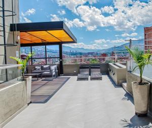eine Dachterrasse mit Stühlen und Stadtblick in der Unterkunft Apartamentos Montecarlo in Medellín