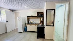 Il comprend une cuisine équipée d'un réfrigérateur blanc et d'un comptoir. dans l'établissement Ariana Apart Hotel Canasvieiras, à Florianópolis