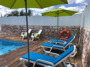eine Gruppe von Stühlen und Sonnenschirmen neben einem Pool in der Unterkunft Hakuna Matata in Cano