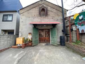 a brick building with a brown door and a window at Stone Lodge 小樽 in Kita-hamachō