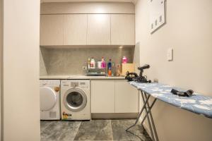una cucina con lavatrice e lavatrice di 5 BDR Flat Bush Mansion - Central Aircon, Fast WiFi, Pool Table, Netflix and More! ad Auckland