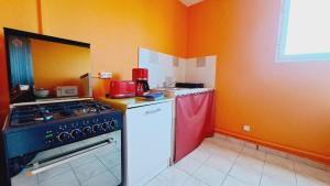 - une cuisine équipée d'une cuisinière et d'un appareil rouge dans l'établissement La Baie de Coreil, à Bouillante