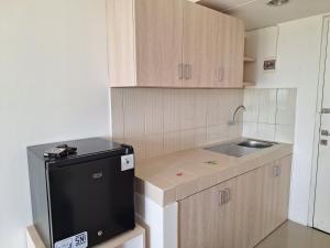 uma pequena cozinha com um lavatório e um frigorífico preto em Grand Sentraland Karawang by DnA Rooms em Karawang