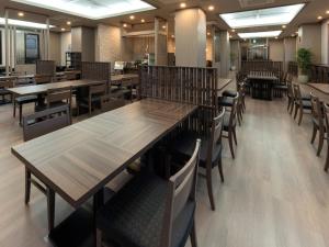 an empty restaurant with wooden tables and chairs at Hotel Route Inn Numata in Numata