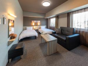 une chambre d'hôtel avec un lit et un canapé dans l'établissement Hotel Route Inn Numata, à Numata