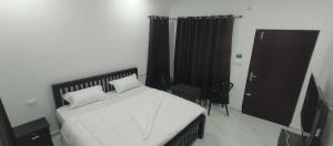 a bedroom with a bed with white sheets and a door at Kashmir Valley in Kanthalloor +4 photos