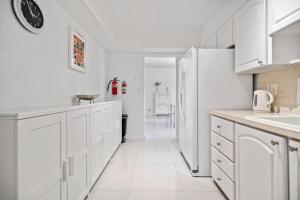 Great Apartment with beach access في هوليوود: مطبخ فيه دواليب بيضاء وثلاجة بيضاء
