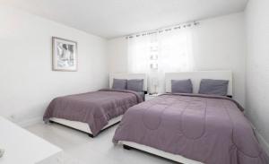 Great Apartment with beach access في هوليوود: سريرين في غرفة بيضاء مع بطانيات أرجوانية