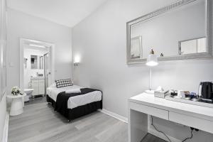 a white bedroom with a bed and a sink at Airport Hotel Sydney in Sydney