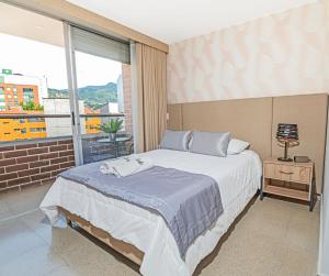 a bedroom with a large bed and a balcony at Apartamentos Montecarlo in Medellín