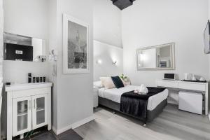 a white bedroom with a bed and a sink at Airport Hotel Sydney in Sydney