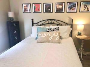 a bedroom with a large white bed with a pillow with the word cozy at The Landing at Hilltop - near ASU & NEA Baptist in Jonesboro