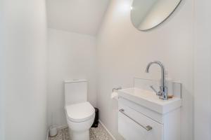 a white bathroom with a toilet and a sink at Retro Retreat in Christchurch in Christchurch