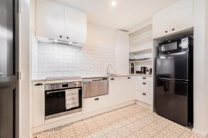 a kitchen with white cabinets and stainless steel appliances at Retro Retreat in Christchurch in Christchurch