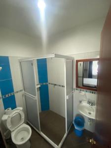 een badkamer met een douche, een toilet en een wastafel bij Hotel Milenium in Yopal