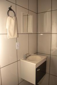 a white bathroom with a sink and a mirror at Pousada Chalés Além do Paraíso in Alto Paraíso de Goiás