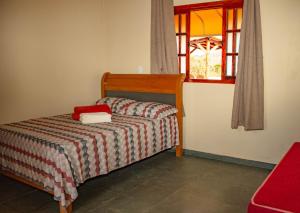 a small bed in a room with a window at Pousada Chalés Além do Paraíso in Alto Paraíso de Goiás