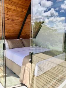 a bed in a room with a glass wall at Rancho Navarro in Pôrto de Pedras