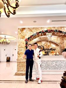 dos hombres parados uno junto al otro frente a una pared en PARADISE HOTEL en Tam Ðảo