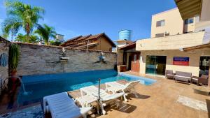 a swimming pool with chaise lounges and chairs near a building at Hotel das Palmas in Florianópolis