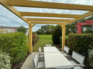 a white table and chairs under a yellow pergola at Maison 2 chambres au calme avec piscine, proche plages et commerces - FR-1-197-484 in Talmont-Saint-Hilaire