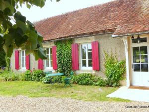 una casa con persianas rojas y un banco en el patio en Gîte Lurcy-Lévis, 2 pièces, 3 personnes - FR-1-489-376, en Lurcy-Lévis