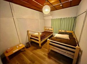 温泉街の入り口にあるゲストハウス SLOW HOUSE yugawara في يوغاوارا: غرفة بسريرين ومصباح