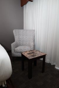 a chair and a coffee table in a room at Northbury Hotel and Conference Centre in Sudbury