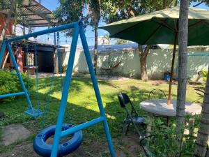 a swing set and an umbrella in a yard at Suite Noa Apartamento in San Pedro Sula