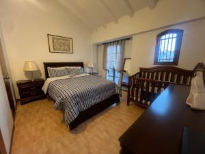 a bedroom with a bed and a table and two windows at Pueblo Viejo Lecheria in El Morro de Barcelona