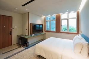 a bedroom with a white bed and a television at Papoa Harbor Hotel in Kaohsiung