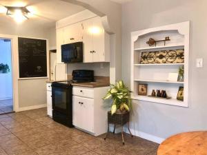 una cucina con armadietti bianchi e stufa nera di Willow Oaks Cottage a Paragould