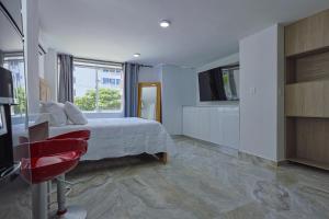 a bedroom with a bed and a red chair at Lujoso Apartamento con salida a la playa in Cartagena de Indias