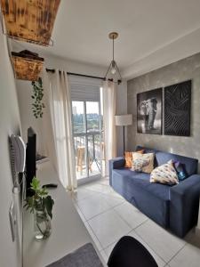 a living room with a blue couch and a window at Studio Lupi in Sao Paulo