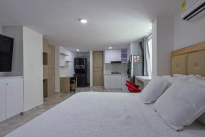 a large white bed in a room with a kitchen at Lujoso Apartamento con salida a la playa in Cartagena de Indias