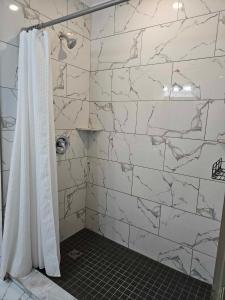 a bathroom with a shower with a white marble wall at France and Flowers Guest House in Stratford