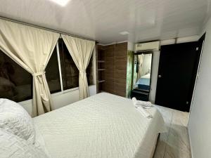 a bedroom with a white bed and two windows at Los Almendros Beach in San Andrés