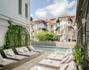 a patio with chaise lounge chairs next to a swimming pool at Maxwell Reserve Singapore, Autograph Collection in Singapore