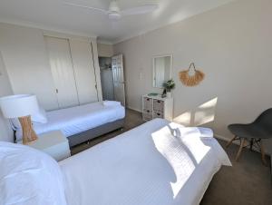 a bedroom with two beds and a desk and a chair at Shoreline Unit 8 in Tuncurry
