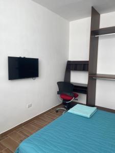 a room with a bed and a tv and a chair at Departamento Bohen 13 in Mérida