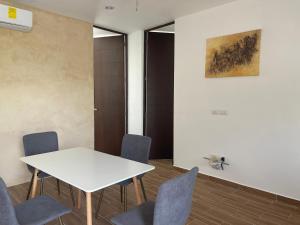 a meeting room with a white table and blue chairs at Departamento Bohen 13 in Mérida