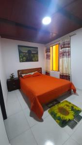 a bedroom with a bed with an orange comforter at Posada lucyta in Consacá