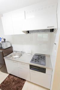 a white kitchen with a stove and a sink at 電車で秋葉原駅11分 東京駅18分 平井駅徒歩8分 in Tokyo