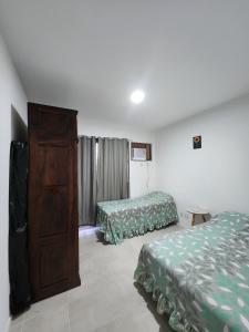 a hotel room with two beds and a dresser at Apartamento com varanda Reserva do Sahy in Mangaratiba