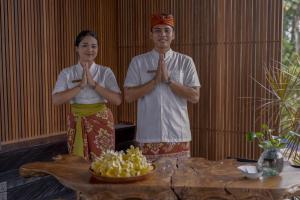 Ein Mann und eine Frau stehen vor einem Tisch. in der Unterkunft Gdas Bali Health and Wellness Resort in Ubud